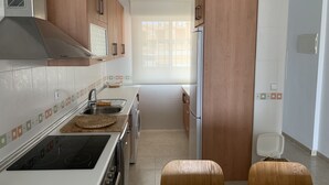A modern kitchen with wooden cabinets, a stainless steel sink, a built-in oven, and a window providing natural light. - Nice and cozy apartment, private parking and sea views in Cabo de Palos. (Cabo de Palos)