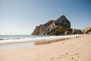 A beach with a rocky outcrop and buildings in the background. - Modern apartment located 200 meters from the sea in the heart of Calpe. (Calpe)