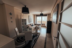 A modern living room with a glass dining table, white sofas, and a black pendant light. - Modern apartment located 200 meters from the sea in the heart of Calpe. (Calpe)