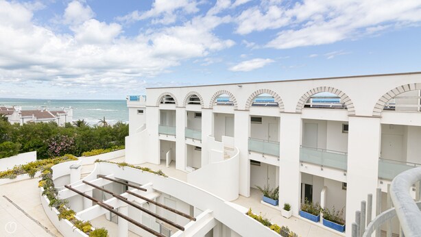 A modern building with multiple balconies overlooking a beach.