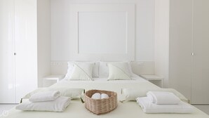 A minimalist bedroom with a large bed, two bedside tables, and a wicker basket on the bed. - Rivazzurra Homes - 52 (Termoli)