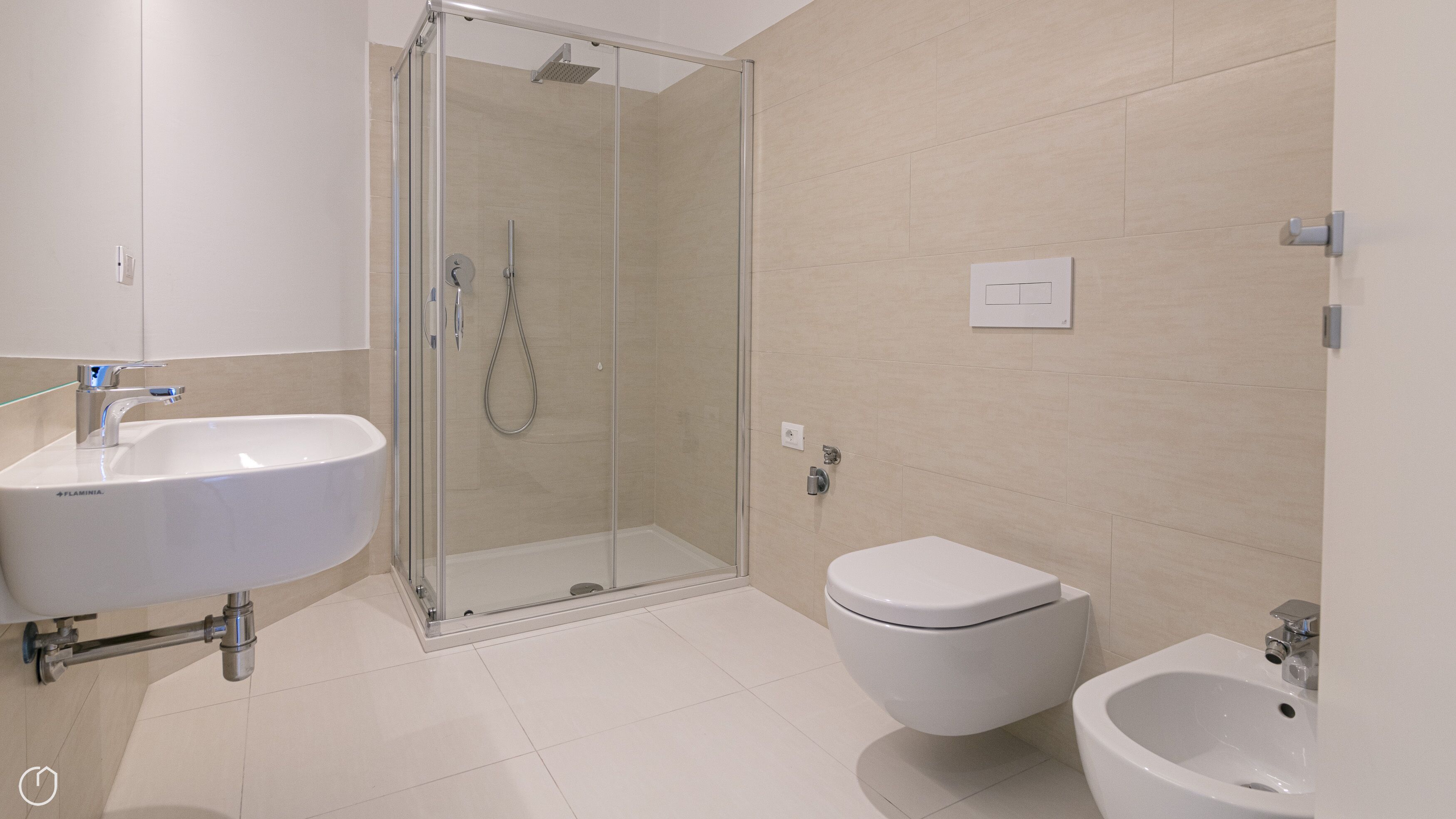Een moderne badkamer met een douchecabine van glas, een witte wastafel, een toilet en een bidet.