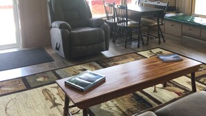 Una sala de estar acogedora con chimenea, un comedor con mesa y sillas, y un ventanal con vistas al exterior.
