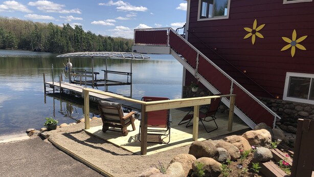 Terraza junto al lago con mobiliario exterior y un muelle que se adentra en el agua.
