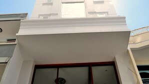 A building with a white facade, a large window with a wooden frame, and a small balcony with a railing. - White Lion Hotel Nha Trang (Nha Trang)