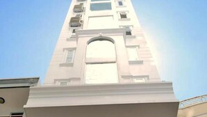A tall, modern building with a central arched entrance and multiple balconies. - White Lion Hotel Nha Trang (Nha Trang)
