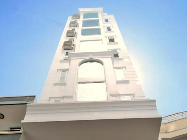 Een hoog, modern gebouw met een centrale gebogen entree en meerdere balkons.