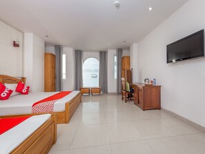 Een hotelkamer met twee houten bedden, een bureau, een stoel, een televisie en een kledingkast.