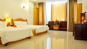 A hotel room with two beds, a wooden headboard, a nightstand, a desk, a chair, and a cabinet. - White Lion Hotel Nha Trang (Nha Trang)