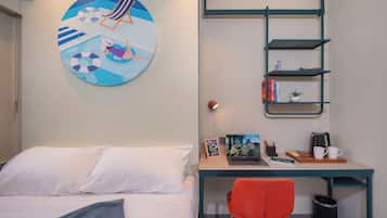 A bedroom with a bed, a desk with a chair, a bookshelf, and a wall with a circular artwork.