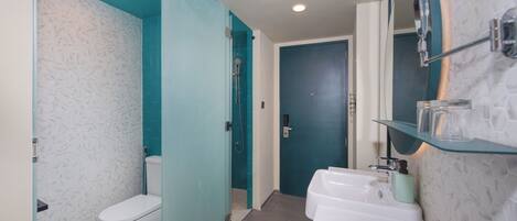 A bathroom with a toilet, shower, and sink.