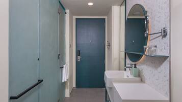 A bathroom with a teal door, white sink, and a mirror with a teal frame.