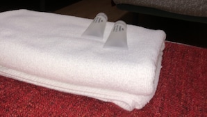 Habitación de hotel con dos camas, cada una con una colcha de cuadros rojos y blancos, y una alfombra roja.