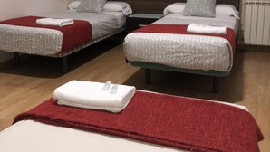 Una habitación de hotel con dos camas individuales, cada una con una manta roja y blanca, y una manta roja en el suelo.