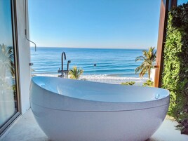 Una bañera independiente grande con vista al océano.