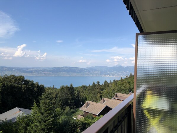 A balcony with a view of a lake and distant mountains.