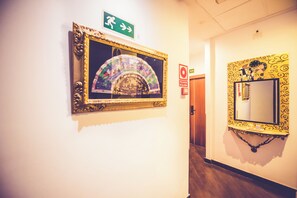 A hallway with two ornate mirrors and a green exit sign.