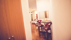 Una porta di legno che dà su una stanza con zona pranzo, con un tavolo rotondo e due sedie.