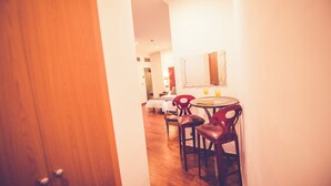 A hotel room with a wooden door, a dining area with a round table and chairs, and a mirror on the wall. - Hostal Sol Los Angeles (Madrid)