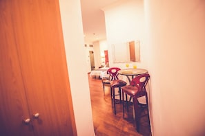 A hotel room with a wooden door, a dining area with a round table and chairs, and a mirror on the wall. - Hostal Sol Los Angeles (Madrid)