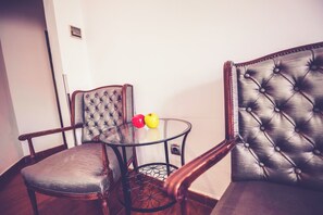 Een kamer met twee leren stoelen, een glazen tafel en twee appels.