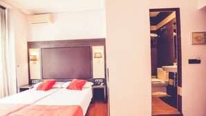 A hotel room with a large bed, bedside lamps, a nightstand, and a view into the bathroom. - Hostal Sol Los Angeles (Madrid)