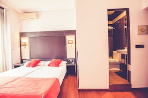 A hotel room with a large bed, bedside lamps, a nightstand, and a view into the bathroom. - Hostal Sol Los Angeles (Madrid)