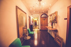 A hallway with a green armchair, a table with a vase, and a door labeled 'SALIDA'. - Hostal Sol Los Angeles (Madrid)