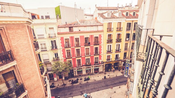 A street view with buildings, a tree, and parked scooters. - Hostal Sol Los Angeles (Madrid)
