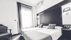 Una camera d'albergo con un letto grande, una sedia, un comodino e una finestra con tende.