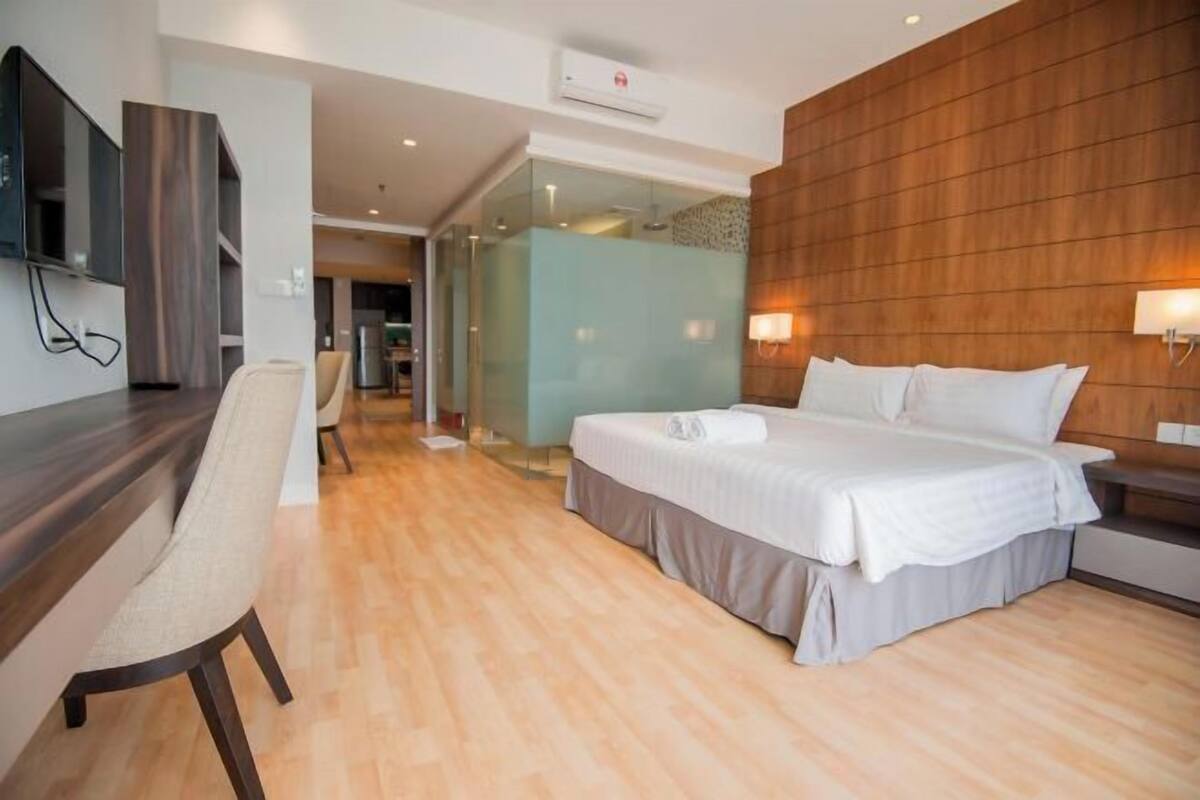 A modern hotel room with a bed, a desk, and a TV.