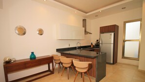 Eine moderne Küche mit Kochinsel, Barhocker, Backofen und Kühlschrank.