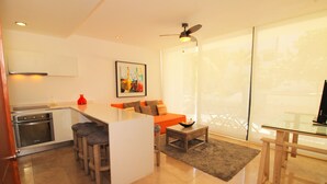 Uma cozinha moderna com uma ilha integrada, banquetas de bar e área de jantar com mesa de vidro e cadeiras.