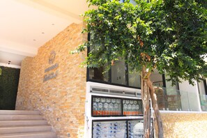 A building with a brick facade, a tree in front, and a staircase leading up.