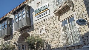 Ein Gebäude mit einer Stein-Fassade, einem Schild mit der Aufschrift 'neva hotel' und einem kleinen Fenster mit einem Metallgitter.