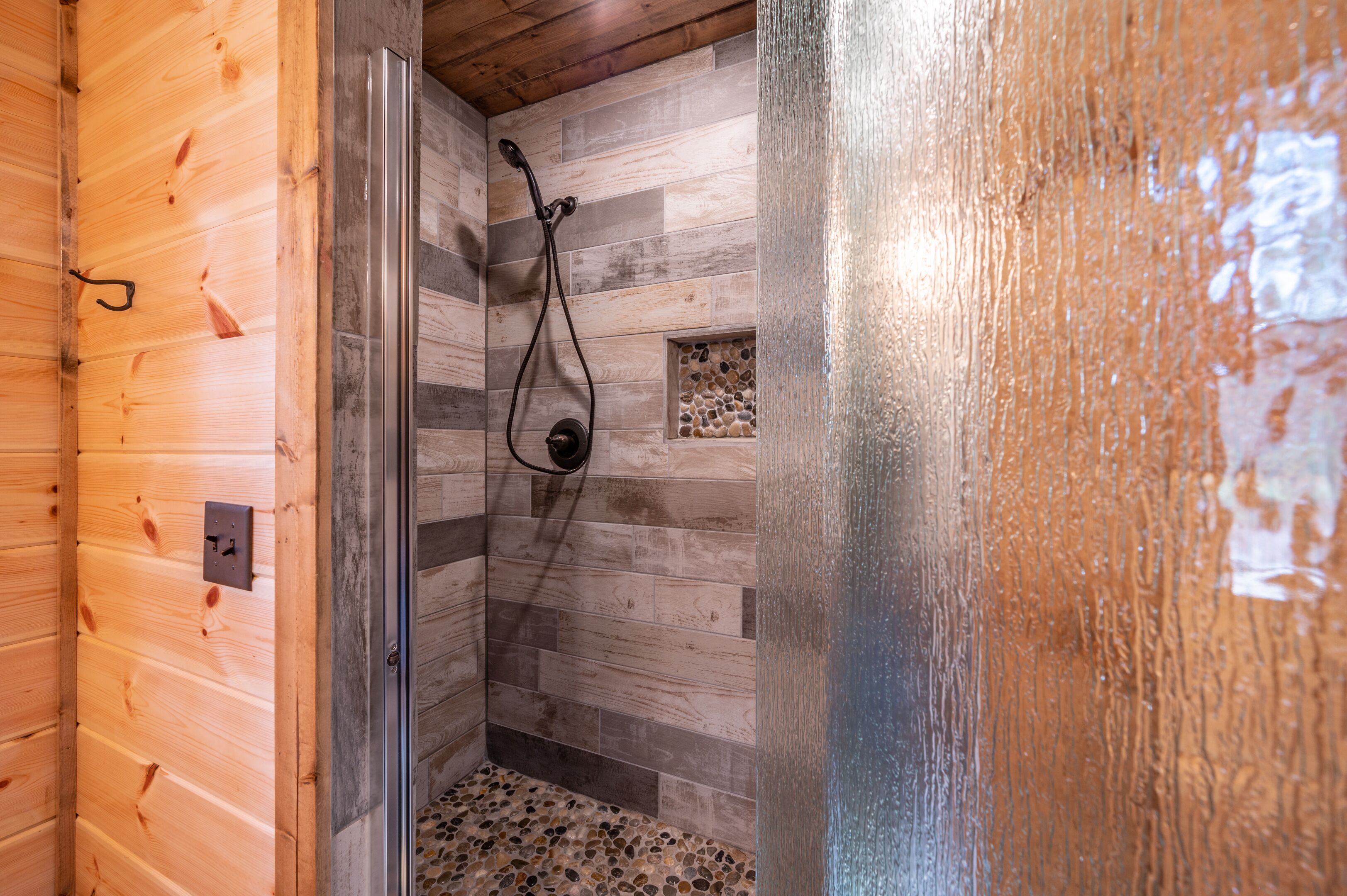L’intérieur d’un chalet en bois comprend un espace douche avec un mur en bois et un sol carrelé.
