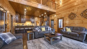 Un intérieur spacieux de chalet en bois, comprenant un espace de vie, une cuisine et un balcon.