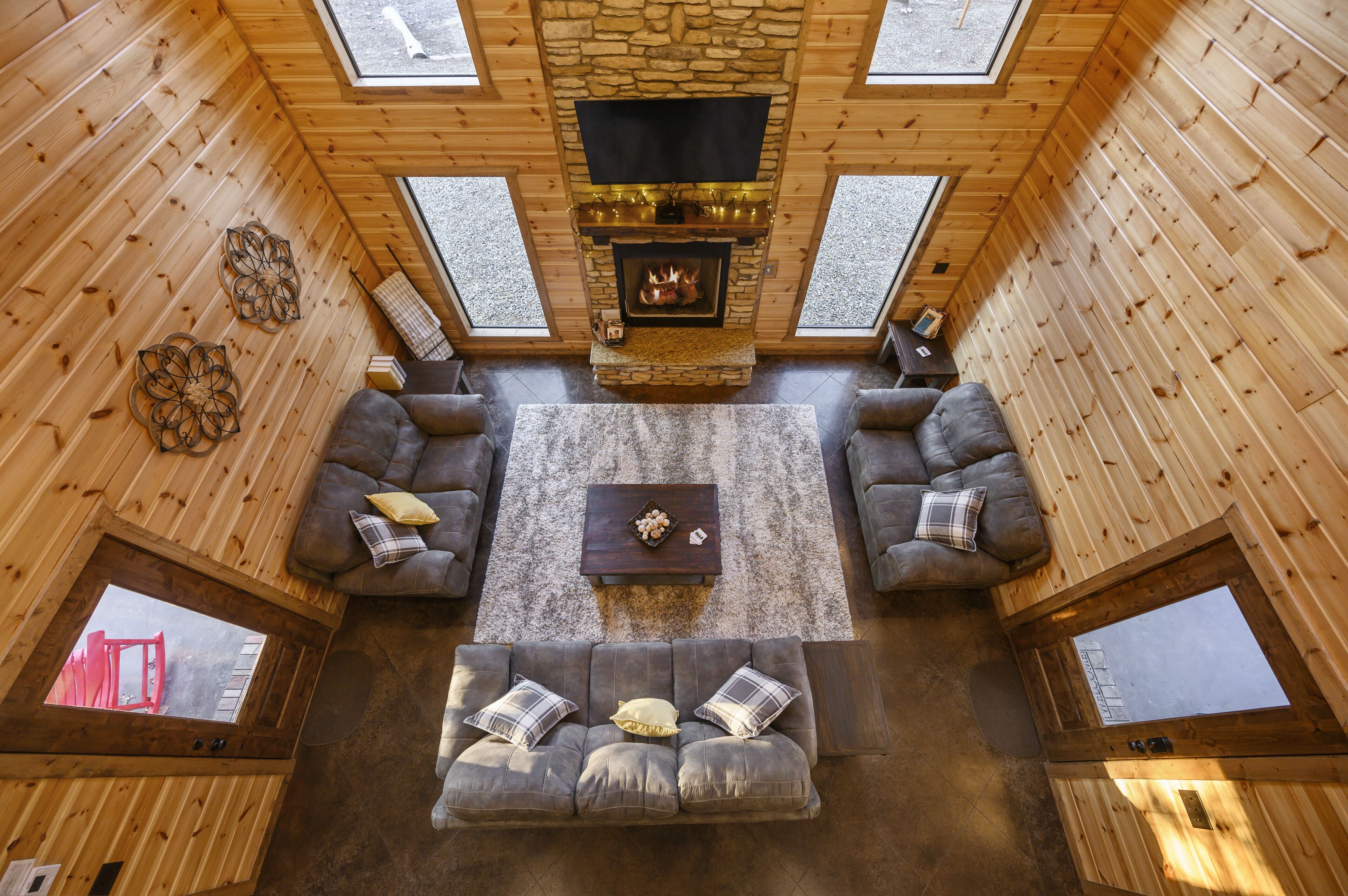L’intérieur d’un chalet confortable, avec une cheminée en pierre, des murs en bois et une grande fenêtre.