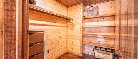 Un intérieur en bois avec un chauffage intégré, un étendoir et une étagère sur laquelle est accroché un panneau indiquant qu'il s'agit d'une buanderie.