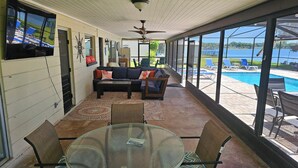 A covered patio with a glass table and chairs, a sofa, and a ceiling fan. - Family Home on Bellows Lake, with new pool.  6505 Walton Way (Tampa)