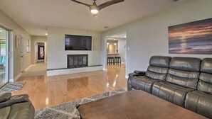 A spacious living room with a fireplace, leather sofa, and a ceiling fan. - Family Home on Bellows Lake, with new pool.  6505 Walton Way (Tampa)