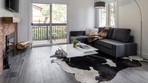 A modern living room with a fireplace, a sofa, a coffee table, and a large window. - Outpost: Sleeping Indian W5 (Teton Village)