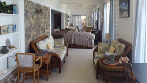 Uma sala de estar ampla com parede de pedra decorativa, móveis de vime e uma cama grande.