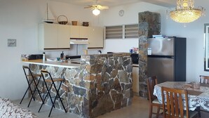 Cozinha moderna com ilha de pedra, armários brancos e lustre.