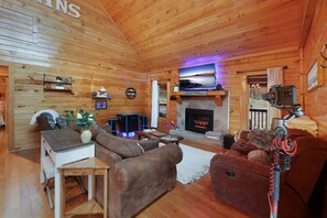 A cozy log cabin interior with a fireplace, wooden furniture, and a mounted camera.