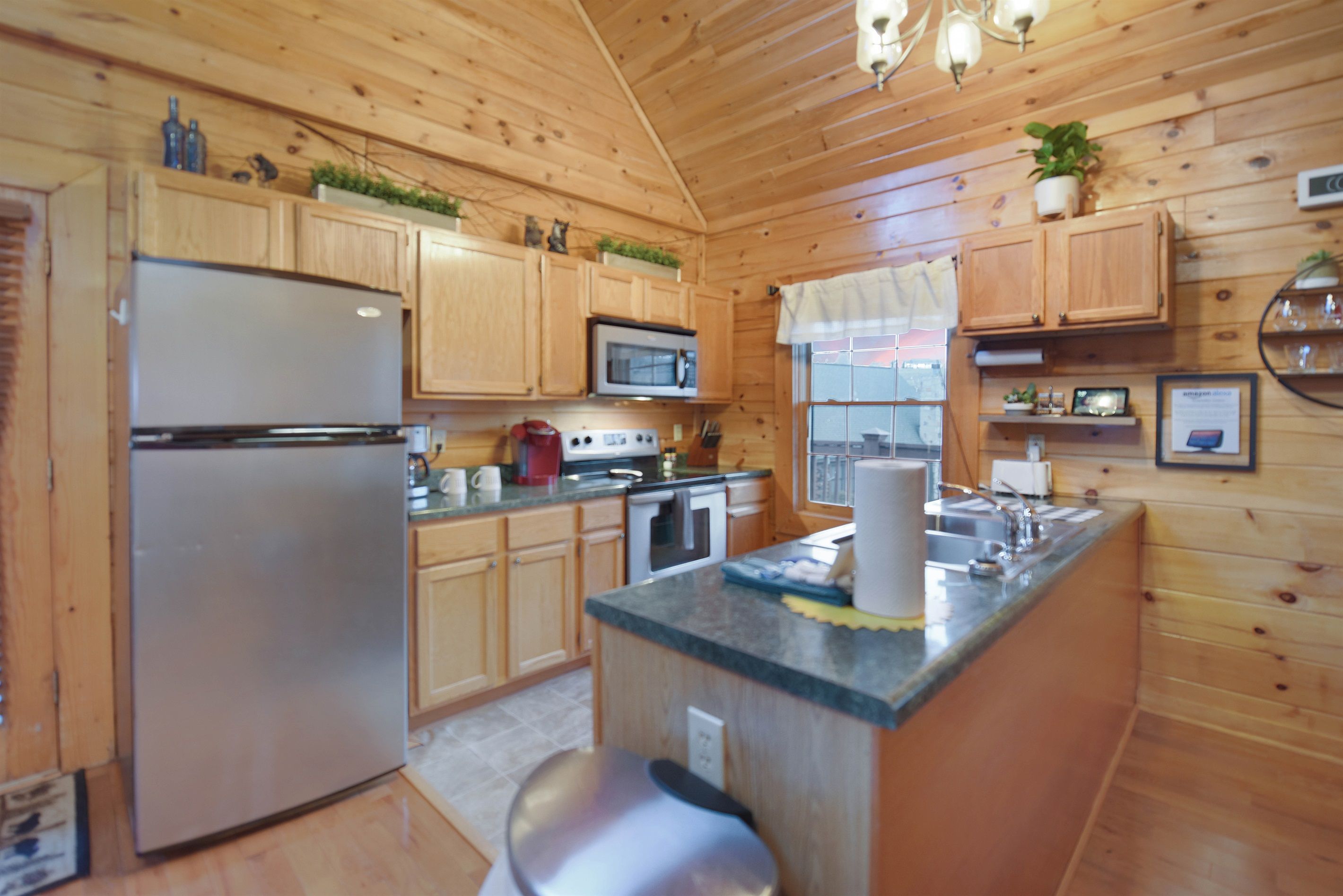 A wooden-paneled kitchen with a refrigerator, stove, microwave, and wooden cabinets.