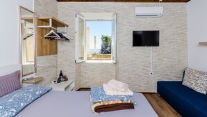 Ein Schlafzimmer mit Bett, Fernseher, Fenster und Holzboden.