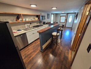 Una cocina moderna con una isla central, electrodomésticos de acero inoxidable y suelo de madera.