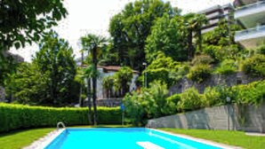 Une piscine rectangulaire à l’eau d’un bleu limpide, entourée de pelouse verdoyante et de haies bien entretenues.