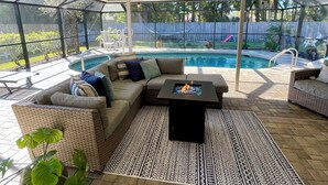 Ein überdachter Patio-Bereich mit Pool, Sitzgelegenheiten im Freien und einem Feuerkorb.